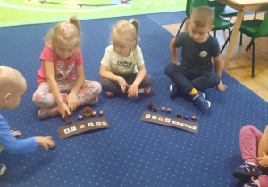 Dzieci siedzą na dywanie i układają rytmy.