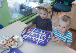 Dzieci siedzą przy stoliku i układają owocowe sudoku.