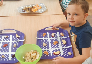 Dzieci siedzą przy stoliku i układają owocowe sudoku.