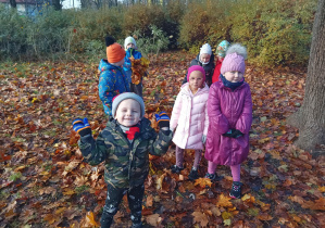 dzieci w parku bawią się jesiennymi liśćmi