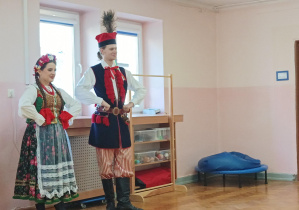 kobieta i mężczyzna ubrani w stroje krakowskie, stoją na sali gimnastycznej