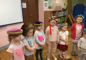 grupa dzieci w czapkach, wiankach- elementach stroju ludowego