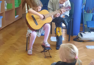 Dziewczynka próbuje gry na gitarze.