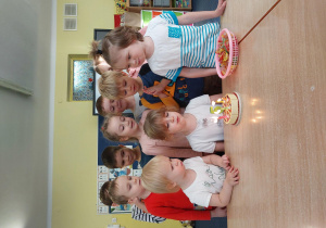 dzieci stoją za stolikiem, na którym widać zabawkowy. urodzinowy tort