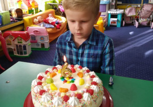 Chłopiec dmucha świeczki na torcie.