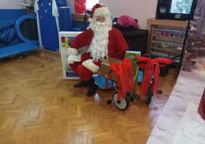 Mikołaj na sali gimnastycznej demonstruje przyniesione prezenty- rowery, bramki