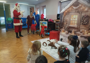 Mikołaj na sali gimnastycznej demonstruje przyniesione prezenty- rowery, bramki