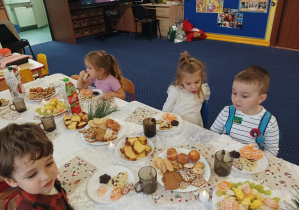 dzieci świętują wigilię przy wspólnym stole