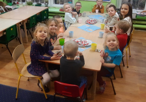 grupa dzieci przy stolikach wspólnie degustuje upieczone ciastka