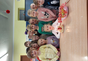 dziewczynka świętuje urodziny, dzieci z jej grupy stoją za nią, na stoliku widać symboliczny tort