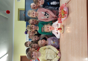dziewczynka świętuje urodziny, dzieci z jej grupy stoją za nią, na stoliku widać symboliczny tort