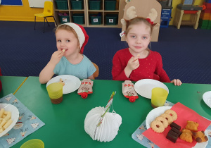 Dzieci siedzą przy stole i zjadają słodkości.