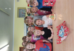 grupa dzieci stoi przy stoliku, na którym widać symboliczny tort