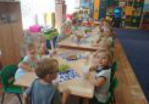 Dzieci z grupy 1 siedzą przy stole zastawionym słodkościami.