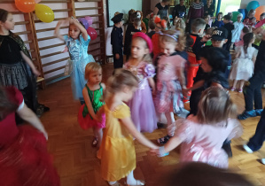 dzieci w przebraniach karnawałowych tańczą na balu przebierańców, na sali gimnastycznej