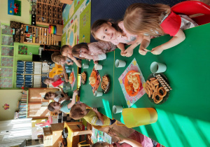 Dzieci siedzą przy stole na którym znajdują się słodycze.