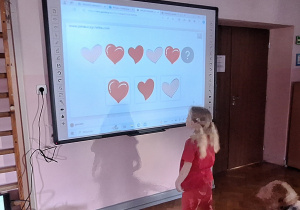 Dziewczynka rozwiązuje zadanie na tablicy interaktywnej.