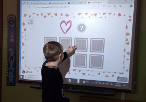 Chłopie wykonuje zadanie przy tablicy interaktywnej.