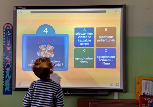 Chłopie wykonuje zadanie przy tablicy interaktywnej.