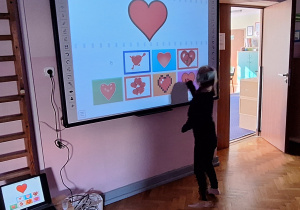 Dziewczynka rozwiązuje zadanie walentynkowe na tablicy interaktywnej.
