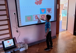 Chłopiec rozwiązuje zadanie walentynkowe na tablicy interaktywnej.