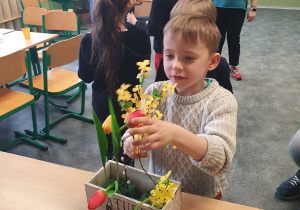 Dzieci ozdabiają kwiatami pojemnik.