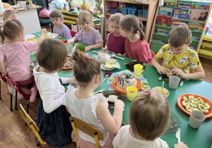 Dzieci siedzą przy stole przy śniadaniu wielkanocnym.
