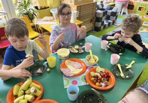 Dzieci siedzą przy stole przy śniadaniu wielkanocnym.