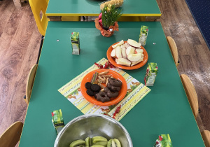 Stół zastawiony owocami i słodkościami.