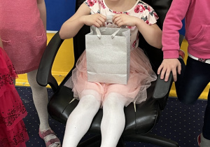 Dziewczynka siedzi na krześle z torbą cukierów.