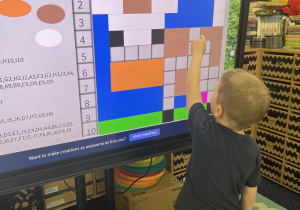 Chłopiec wykonuje zadanie przy tablicy interaktywnej.