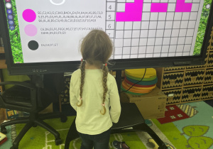 Dziewczynka wykonuje zadanie przy tablicy interaktywnej.