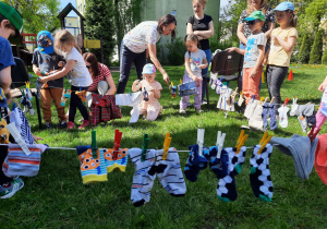 Dzieci wieszają pranie na sznurkach.