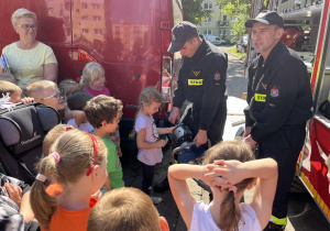 Dziewczynka obsługuje rozpierak z pomocą strażaka.