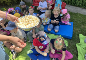 Dzieci zjadają popcorn w przerwie między zabawami.