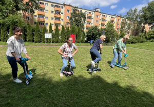 Nauczycielki prezentują hulajnogi do zabawy w ogrodzie.