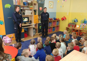 Dzieci z grupy 1 i 2 oglądają film edukacyjny wraz z policjantkami i odpowiadają na pytania.