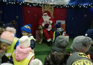 Mikołaj rozdaje dzieciom cukierki.