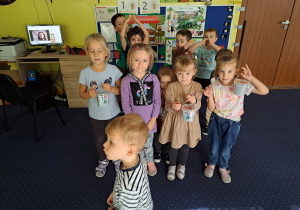 dziewczynki i chłopcy pozują do wspólnego zdjęcia, dziewczynki trzymają prezenty