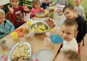 Dzieci siedzą przy stole na którym stoją słodkości.