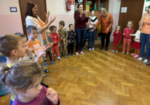 Dzieci ustawione w kole bawią się przy muzyce.