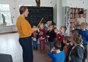 dzieci znajdują się w bibliotece, pani bibliotekarka wręcza dzieciom kartę biblioteczną