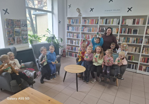 dzieci w bibliotece pozują do zdjęcia na tle regałów z książkami