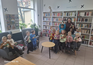 dzieci w bibliotece pozują do zdjęcia na tle regałów z książkami