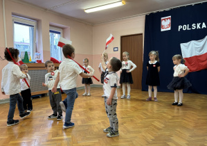 Dzieci śpiewają piosenkę patriotyczną i maszerują do niej.