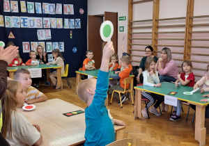 Dzieci siedzą przy stolikach i wykonują zadania.