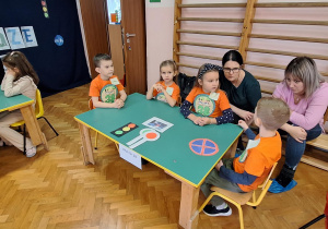 Dzieci siedzą przy stolikach i wykonują zadania.