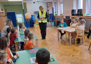 Dzieci siedzą przy stolikach i odpowiadają na pytanie.