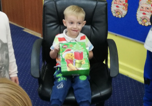 Szymon siedzi na krześle z torbą cukierków dla dzieci.