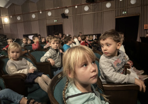 Dzieci siedzą na sali teatralnej.